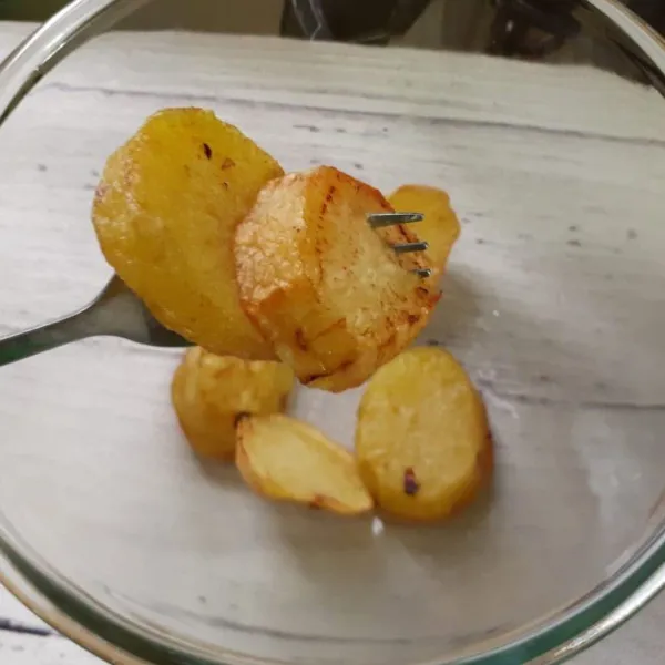 Kupas kentang, potong-potong lalu goreng kentang dan bawang putih utuh sampai setengah kering (jika kentang digoreng akan menghasilkan perkedel yang pulen).