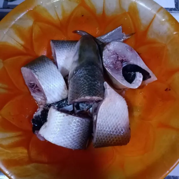 Potong ikan sesuai selera. Beri perasan air jeruk nipis dan diamkan selama 15 menit.