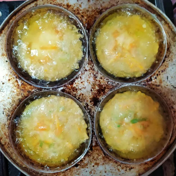 Saya tidak punya cetakan weci jadi pakai cetakan cara bikang. Beri minyak 1/2 cetakan dan panaskan dengan api kecil. Panaskan juga wajan dengan minyak yang agak banyak. Setelah cetakan cara bikang panas, tuang 1 sendok sayur adonan. Tunggu hingga bagian bawah berkulit.