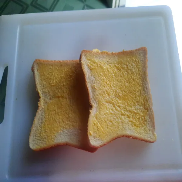 Olesi kedua sisi roti dengan margarin
