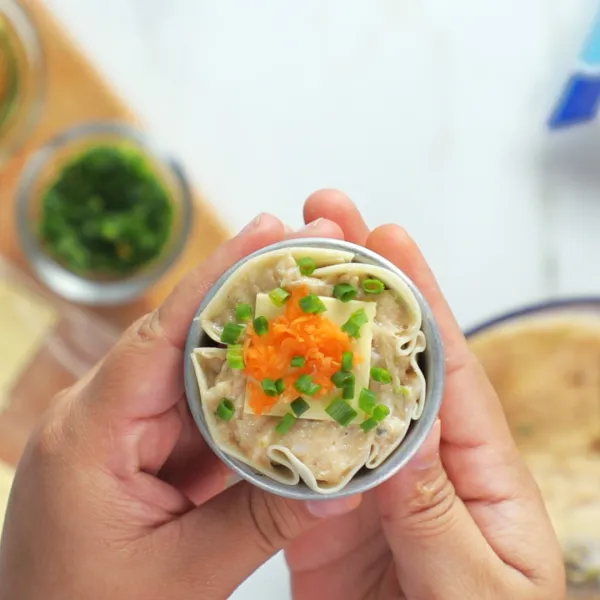 Beri topping Anchor Cheese Sliced, wortel parut dan daun bawang di atas dumpling.