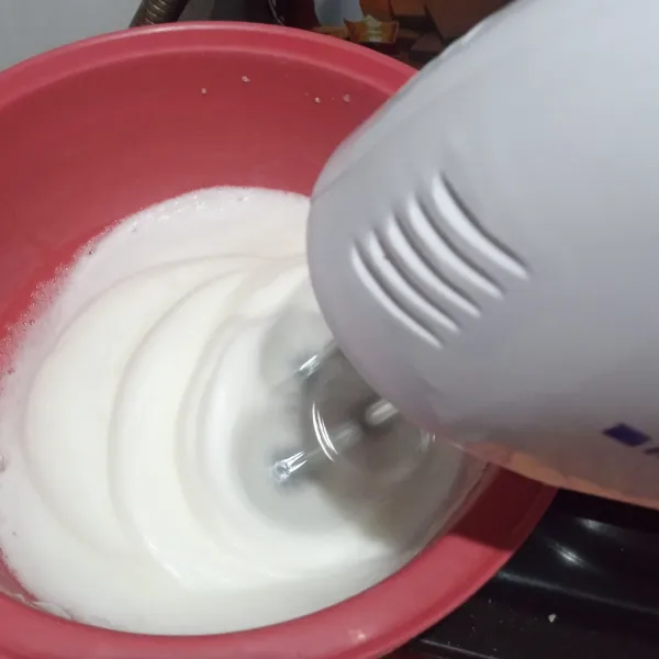 Mixer putih telur dengan kecepatan tinggi sampai mengembang.