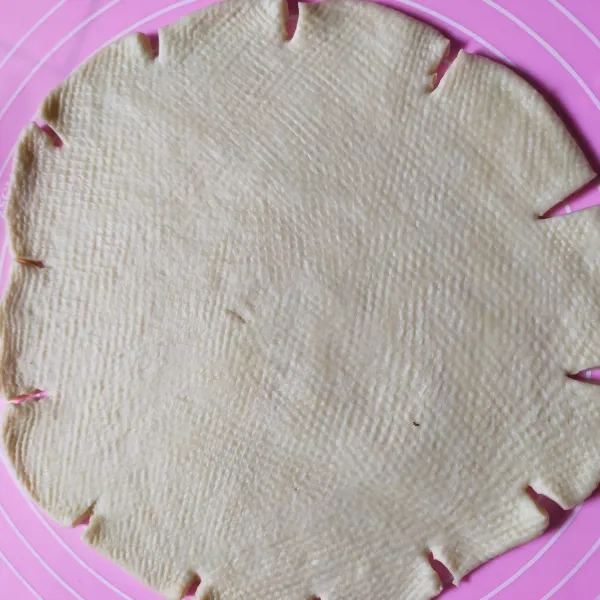 Ambil sekitar 250 gram adonan, pipihkan berbentuk bulat. Lalu gunting pinggir pinggirnya. Letakkan dalam loyang pizza ukuran 18.