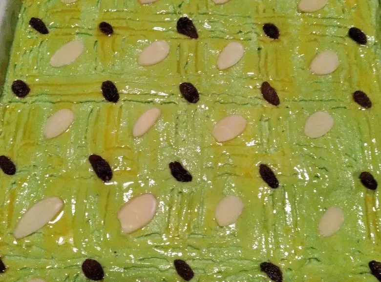 Olesi bagian atas dengan kuning telur, garis dengan garpu tata almond dan kismis