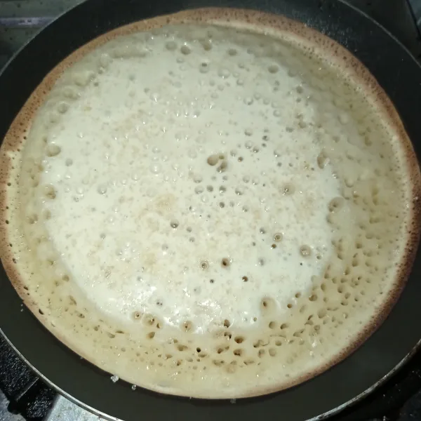 Tuang pada teflon yang sudah dipanaskan terlebih dahulu, tunggu gelembung keluar lalu taburi gula pasir, tutup biarkan sampai matang.