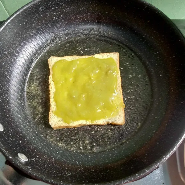 Panaskan mentega pada teflon. Letakkan selembar roti tawar yang diolesi dengan selai matcha.