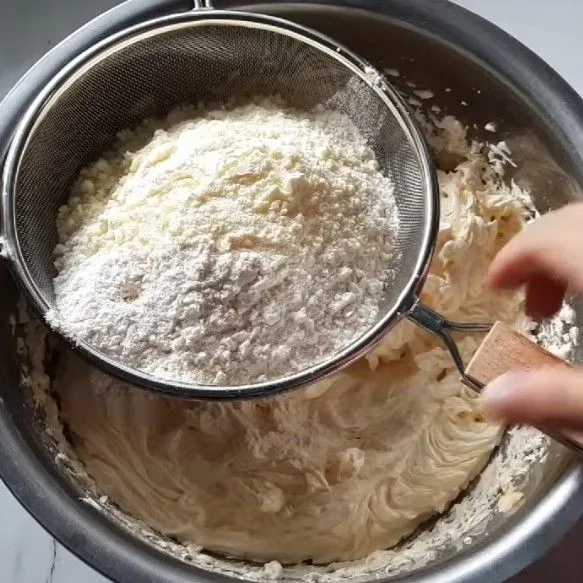 Tambahkan tepung terigu dan susu bubuk sambil disaring.