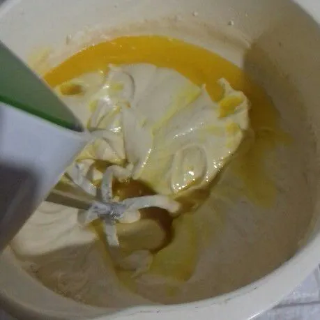 Masukkan margarin cair, kocok asal rata. Matikan mixer dan ratakan dengan spatula.