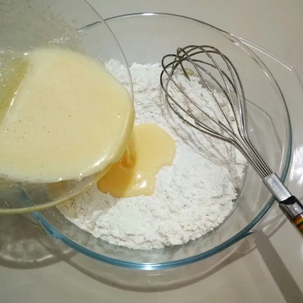 Lalu tuang adonan telur ke dalam mangkok campuran tepung, aduk asal rata.