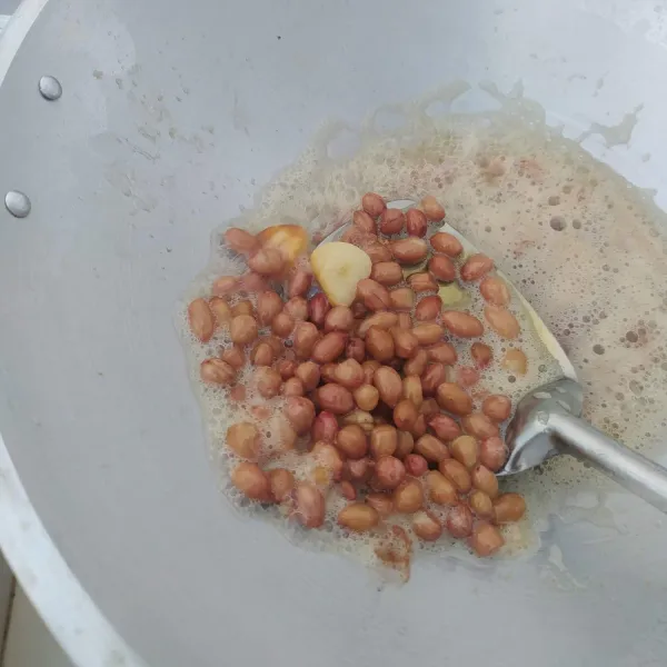 Cuci kacang tanah hingga bersih, kemudian tiriskan. Goreng kacang dan bawang putih hingga matang, tiriskan dan biarkan dingin.