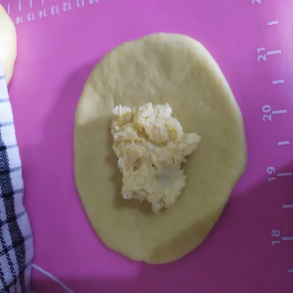 Ambil 1 buah adonan, gilas dengan rolling pin sampai pipih beri isian, kemudian tutup rapat dan bulatkan kembali sambil dicubit cubit agar isian tidak bocor, tata sebanyak 9 bulatan di loyang berukuran 20x20 cm yang sudah diolesi margarin atau dialasi kertas baking