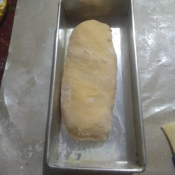 Gulung satu bagian roti. masukkan kedalam loyamg yang sudah diolesi margarin dan ditaburi tepung terigu tipis-tipis.
