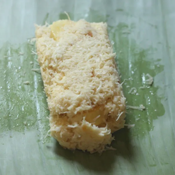 Ambil selembar daun pisang sekitar 2-3 sdm adonan, selipkan beberapa potong pisang lalu bentuk persegi panjang tegak.