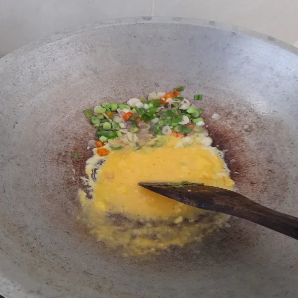 Sisihkan tumisan bawang di bagian tepi wajan, masukkan telur yang sudah dikocok, masak sambil diorak-arik