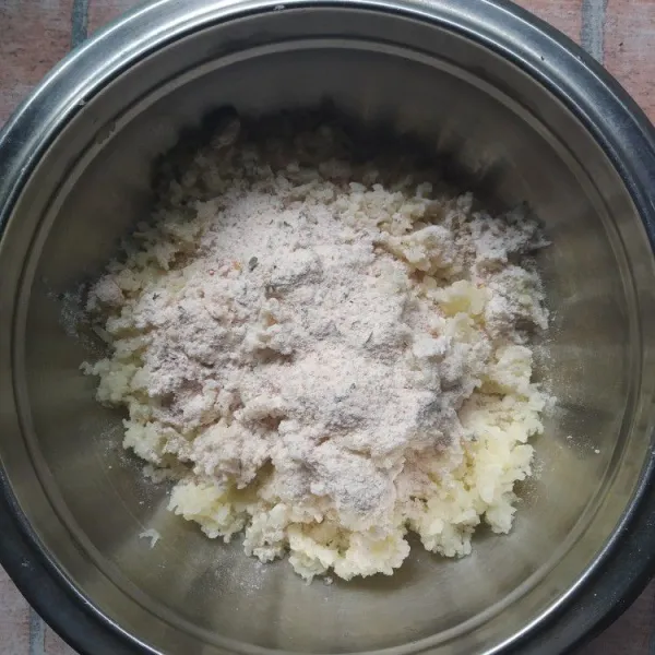 Tambahkan tepung terigu, bawang putih bubuk, kaldu bubuk, cabe bubuk dan parsley kering ke dalam kentang yang sudah diparut.