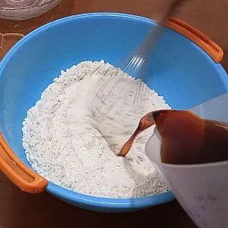 Di wadah lain campur terigu, baking soda, baking powder, dan garam. Aduk rata, masukkan air gula sedikit demi sedikit.