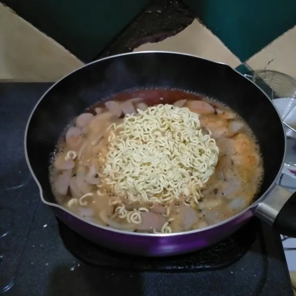 Selanjutnya, masukkan sosis, bakso, dan mie kuning hingga setengah matang.