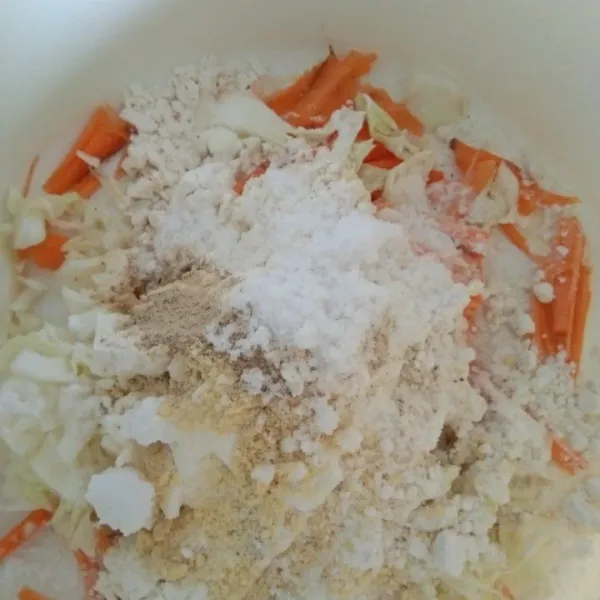 Dalam wadah campur tepung terigu, tepung tapioka, irisan kol, wortel, garam, kaldu jamur, merica bubuk dan bawang putih bubuk, aduk rata
