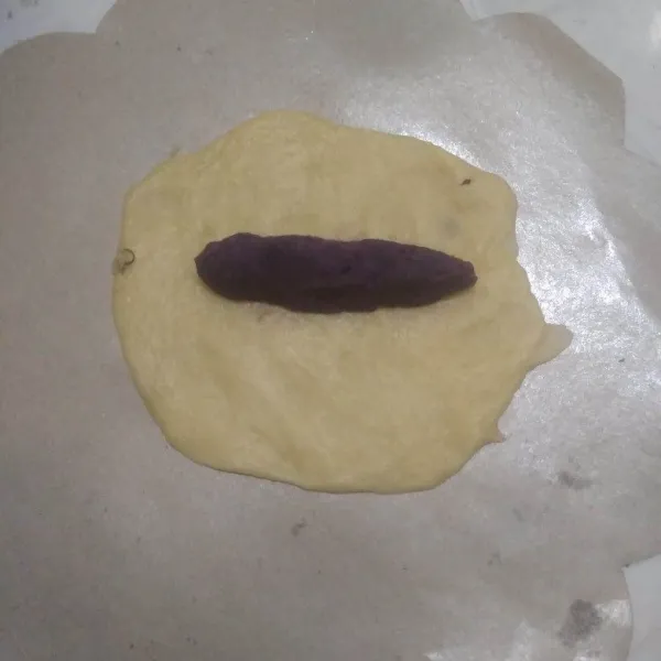Ambil satu bagian roti, pipihkan lalu beri isian ubi ungu yang dipilin memanjang. Lipat. Gilas memanjang.