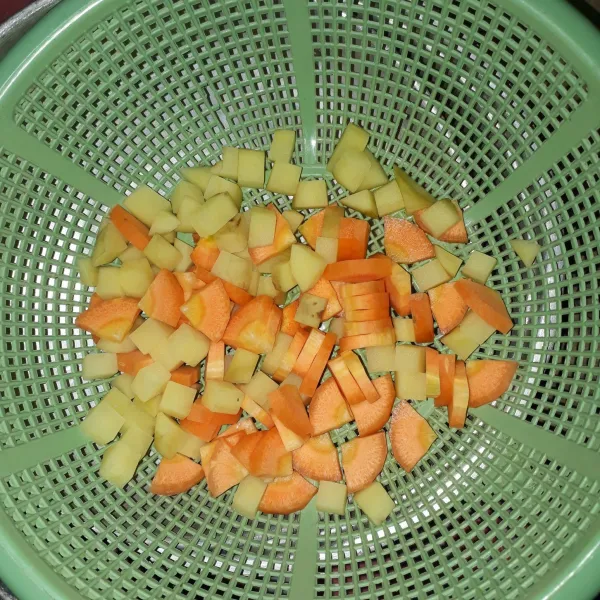 Potong-potong kentang dan wortel, lalu cuci bersih dan tiriskan.