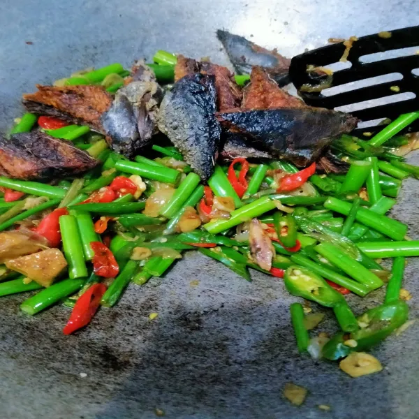 Setelah itu, masukkan pindang tongkol yang sudah digoreng, aduk rata. Tambahkan kaldu jamur dan merica bubuk. Koreksi rasa. Masak hingga daun bunga bawang empuk. Matikan api. Salin ke piring saji.