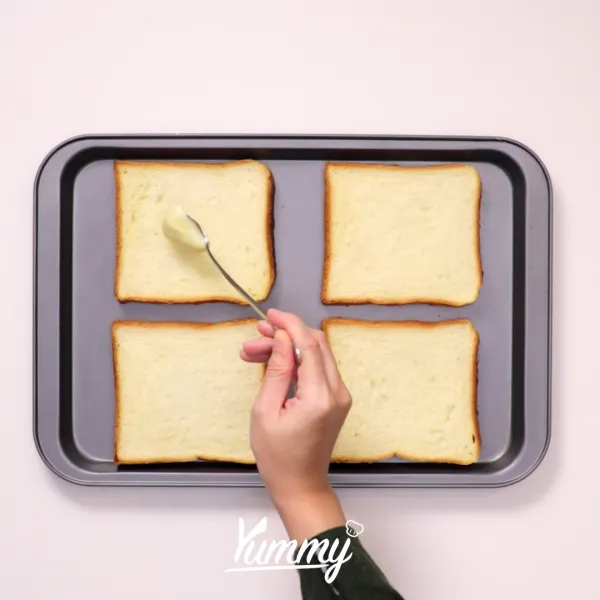 Oleskan milky cheese di atas roti secara merata, kemudian taburkan dengan gula pasir.