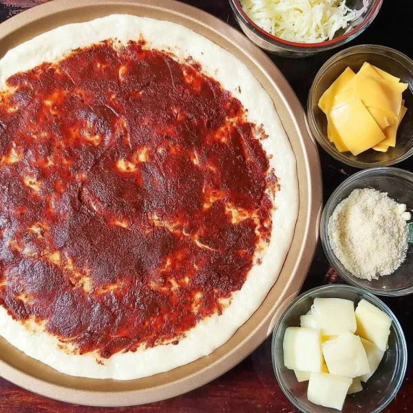 Olesi adonan dengan saus pizza, kemudian taburkan keju mozarella parut dan keju parmesan bubuk. Panggang sampai 3/4 matang, waktunya tergantung oven masing-masing.