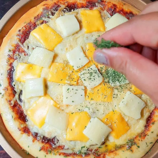 Keluarkan pizza lalu letakan keju american cheddar dan keju mozarella iris diatasnya, taburkan daun parsley juga. Campur bahan olesan kemudian oleskan pinggiran pizza. Masukan pizza kembali ke dalam oven, panggang sampai keju meleleh.