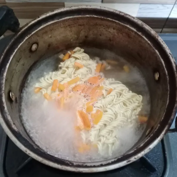 Rebus mie bersama wortel sampai matang. Kemudian tiriskan.