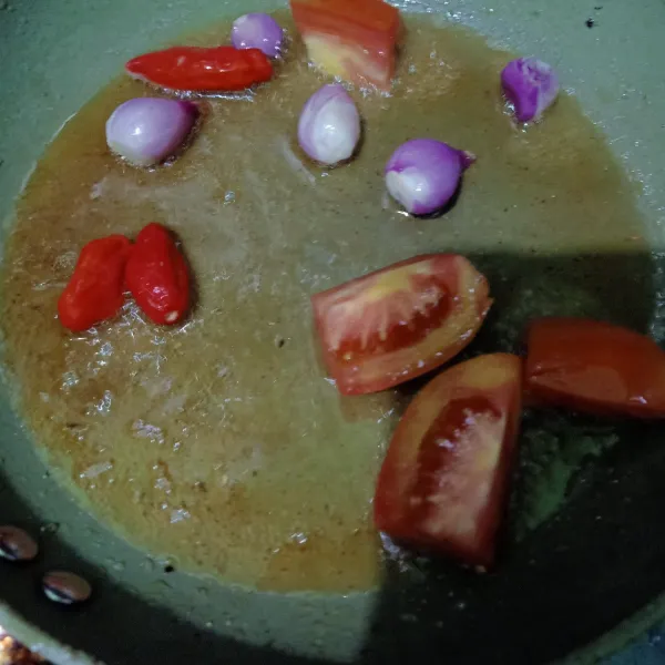 Kupas bawang merah lalu cuci tomat dan cengek, tiriskan. Siapkan wajan beri minyak sedikit lalu panaskan, setelah minyak panas masukan tomat, cengek dan bawang merah. Oseng sampai setengah matang lalu angkat.