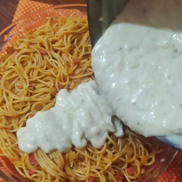 Tuang spaghetti di wadah tahan panas lalu tuang saus putih di atasnya. Ratakan.