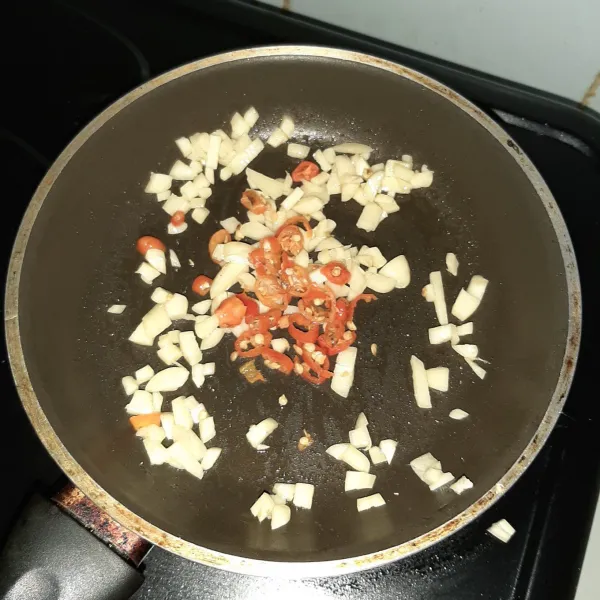 Tumis bawang putih dan cabai rawit merah hingga harum.