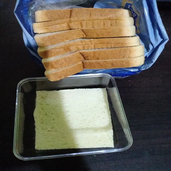 Potong roti sesuai ukuran wadah. Hilangkan bagian pinggirannya.