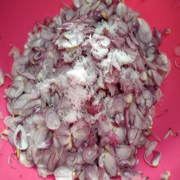 Kupas bawang merah, tidak usah dicuci. Lalu iris bawang merah, dengan alat pengiris bawang. Taburi dengan garam, aduk rata.