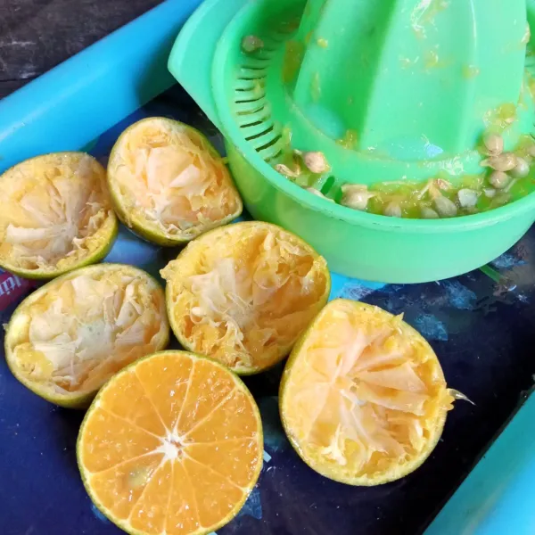 Belah dua buah jeruk, lalu peras dan ambil airnya.