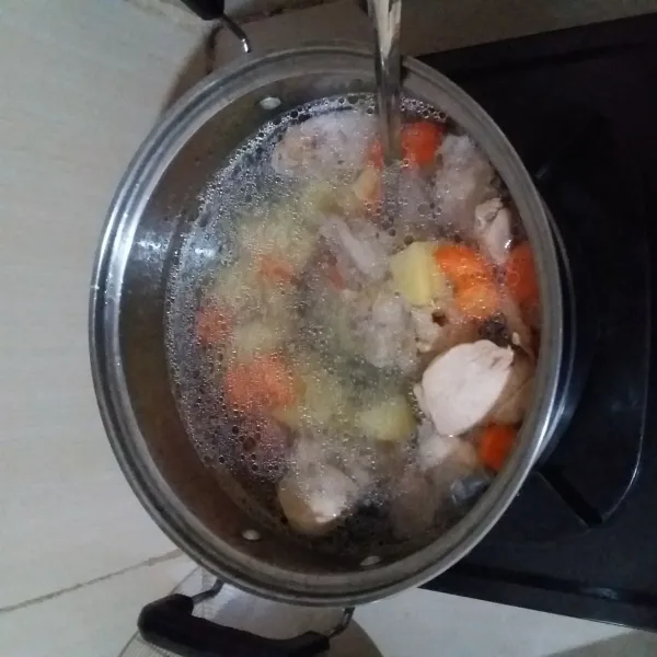 Masukan bumbu tumis ke dalam air rebusan ayam. Masukan wortel dan kentang. Rebus hingga matang
