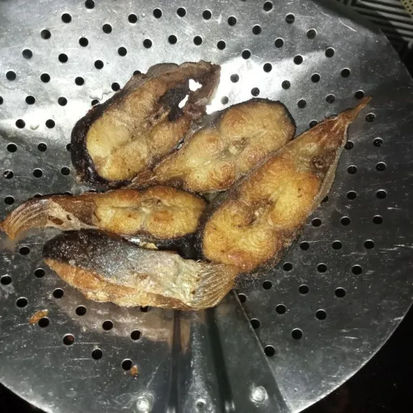 Lumuri ikan dengan garam dan jeruk nipis, lalu goreng ikan hingga matang.