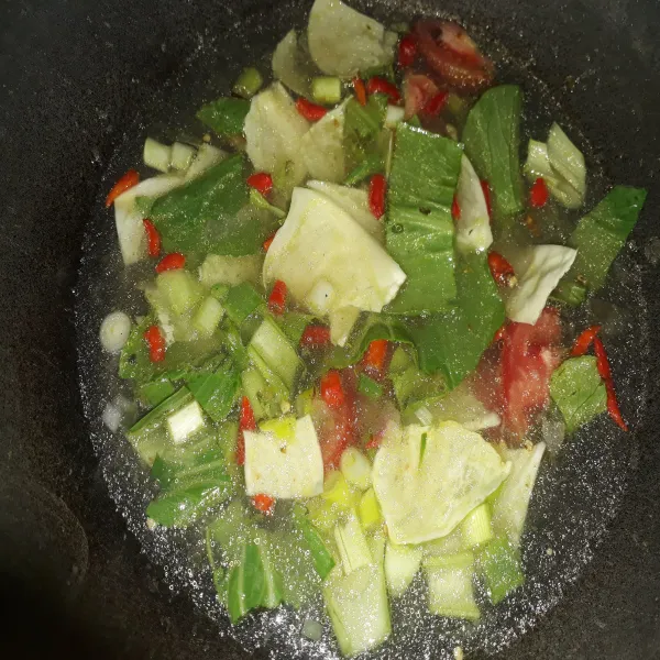 Tuang air, masukan potongan kol, pokcoy, tomat dan cabe rawit merah. Masak hingga sayuran layu.