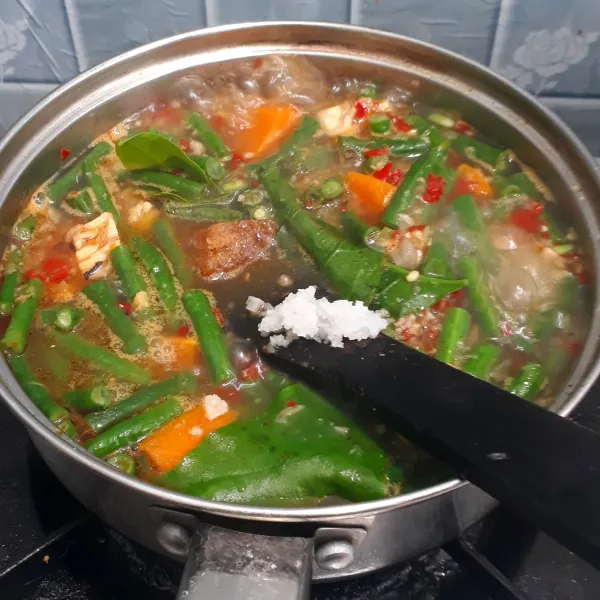 Masukkan daun melinjo, garam, dan gula merah. Masak hingga daun melinjo agak layu.