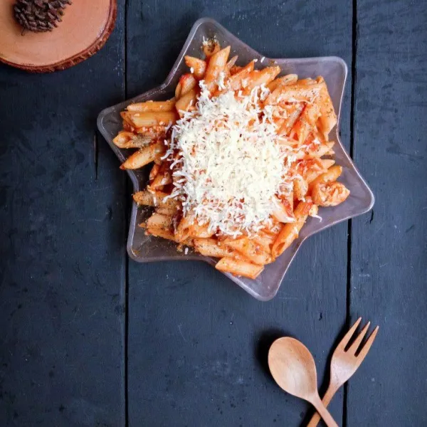 Sajikan dengan keju cheddar parut sisanya dan taruh di atas penne.