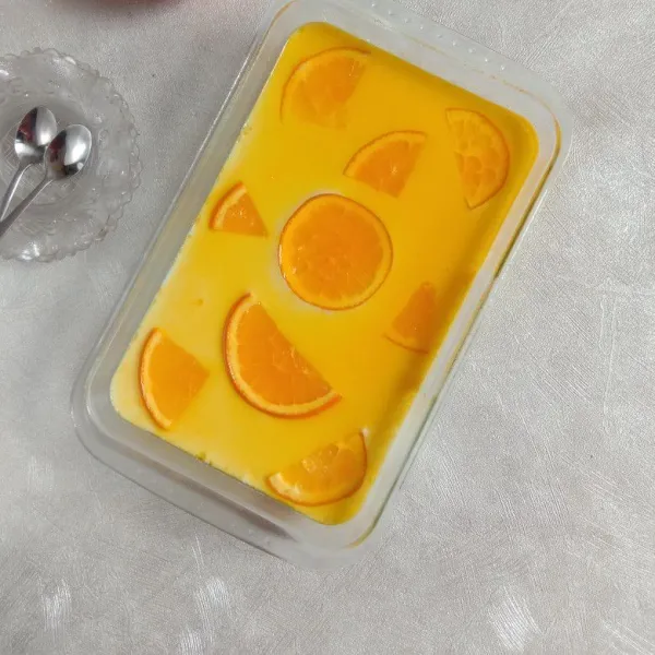 Tuang air perasan jeruk/orange jus di atas puding.
