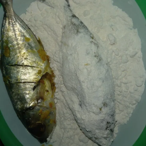 Campur tepung terigi dan tepung beras. Balur ikan dengan campuran tepung hingga merata.