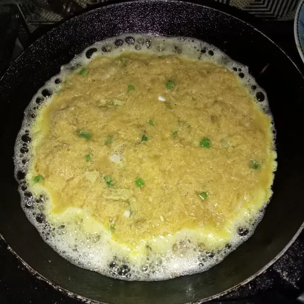 Panaskan minyak goreng diwajan, lalu tuang adonan telur dan ratakan.