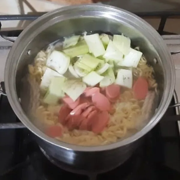 Masukan batang pakcoy dan irisan sosis. Masak hingga batang pakcoy matang.