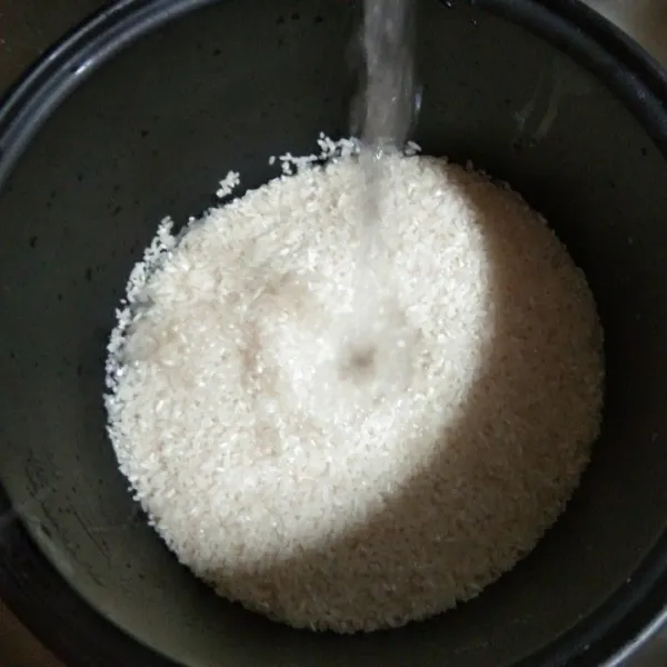Cuci bersih beras dalam panci magic com, buang air bilasannya