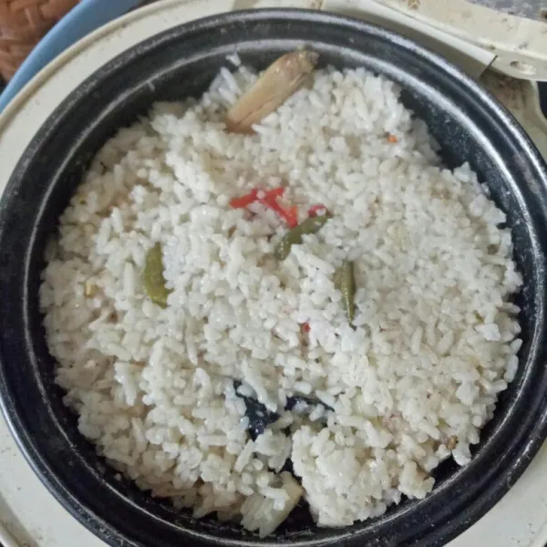 Setelah tombol berpindah, aduk rata nasi.  Tunggu nasi hingga benar-benar matang.