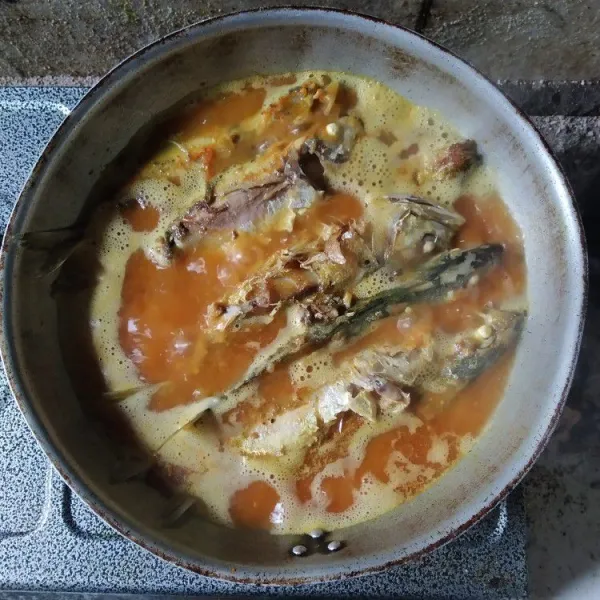 Masukkan ikan kembung yang sudah digoreng, tambahkan kembali air, biarkan mendidih, bumbui dengan garam, penyedap dan gula pasir, jangan terlalu sering diaduk agar ikan tidak hancur.