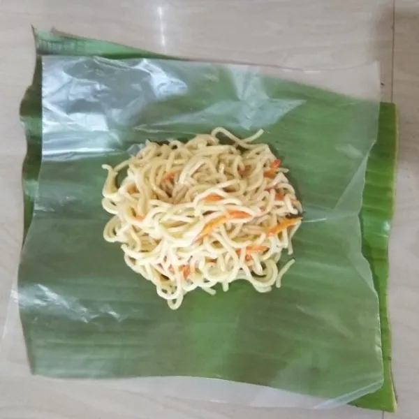 Siapkan daun pisang untuk alas, lalu beri plastik lagi di atasnya. Tuang 1½ sendok makan adonan mie. Bungkus menggunakan daun pisang. Lalu semat tusuk giginya.