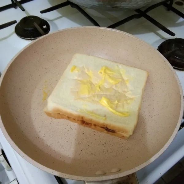 Panaskan margarin di teflon, tata tangkupan roti, olesi bagian atas roti dengan margarin secukupnya
