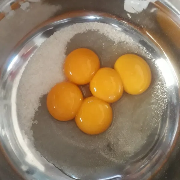 Dalam baskom besar, masukkan telur utuh, kuning telur, dan gula.